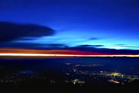 富士山頂からの夜明け、街の灯りとオレンジの地平線