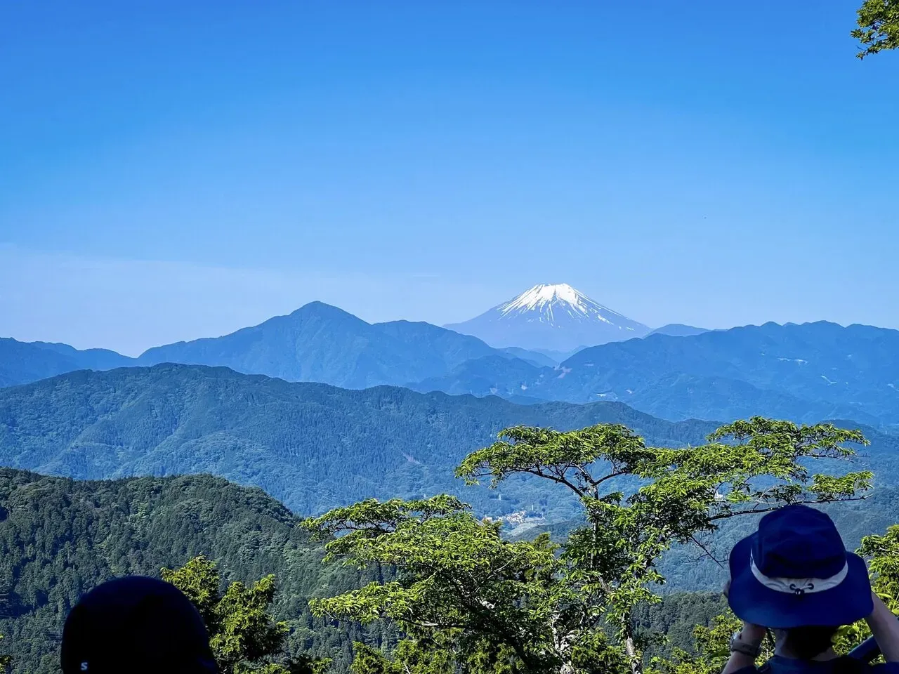 青い山並みの奥に雪を被った富士山